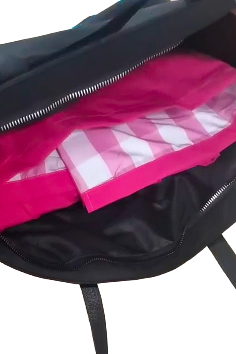 An open Free Gift Urban Slate Waterproof bag in black reveals a pink and white checkered item inside, partially visible through the unzipped opening for organized packing.