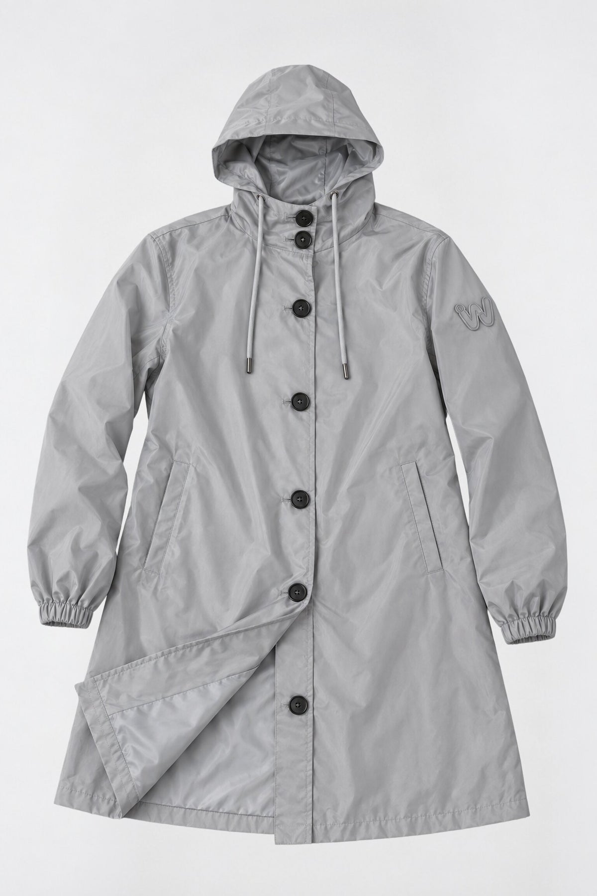 The Icon Milano Windbreaker Rain Jacket is a light gray, water-resistant women’s coat with black buttons, front pockets, and an embroidered “W” on the left sleeve, laid flat on a plain background. This longline rain jacket features a drawstring hood and elastic cuffs for added windproof outerwear protection.
