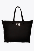 The Free Gift Urban Slate Waterproof bag is a spacious black tote with two handles and a white "W" embroidered on top. Designed for smart organization, this travel duffel keeps essentials tidy against its crisp white background.