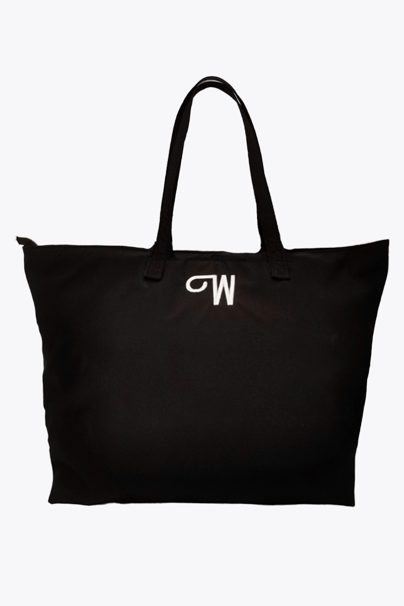 The Free Gift Urban Slate Waterproof bag is a spacious black tote with two handles and a white "W" embroidered on top. Designed for smart organization, this travel duffel keeps essentials tidy against its crisp white background.