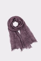 The Lightweight Linen Scarf, in crinkled purple linen with a textured finish, is shown laid flat with one end coiled on a plain white background—a versatile accessory for all seasons.